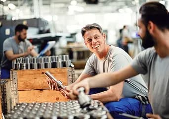 Machinists checking machined parts at a workbench