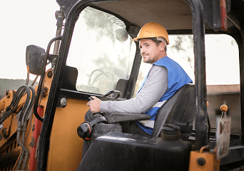 A driver in a hard hat at the wheel of a truck