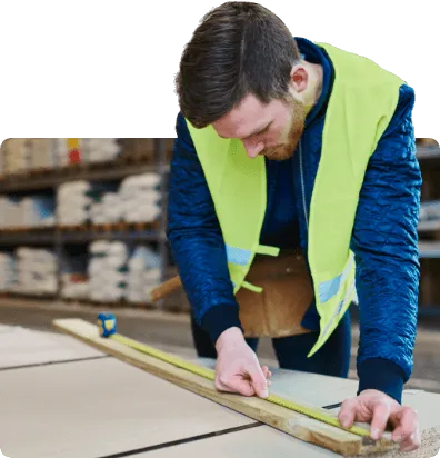 Trades person measuring a wood with a tape measure
